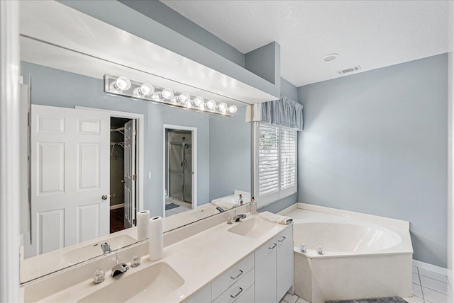 bathroom with a bath, vanity, a textured ceiling, and tile patterned floors