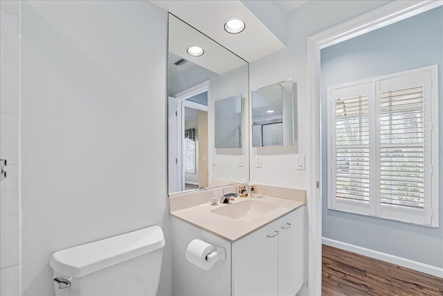 bathroom featuring a wealth of natural light, vanity, hardwood / wood-style flooring, and toilet