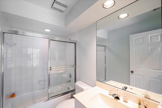 full bathroom featuring toilet, combined bath / shower with glass door, and vanity