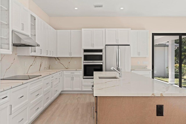 kitchen with white cabinets, appliances with stainless steel finishes, a center island with sink, and sink