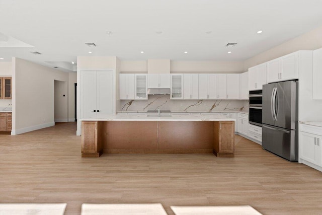 kitchen with a kitchen island with sink, appliances with stainless steel finishes, and light hardwood / wood-style flooring