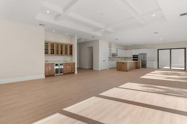 unfurnished living room with light hardwood / wood-style floors, beverage cooler, beam ceiling, and coffered ceiling