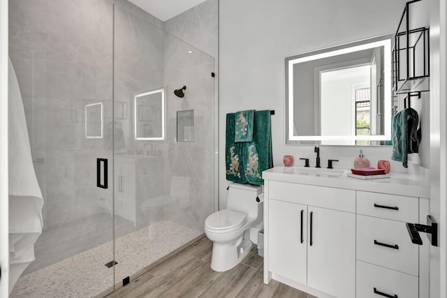 bathroom featuring a shower with shower door, hardwood / wood-style floors, toilet, and vanity