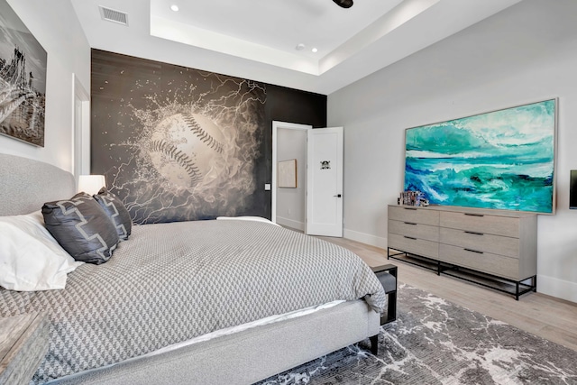 bedroom featuring wood-type flooring and a raised ceiling