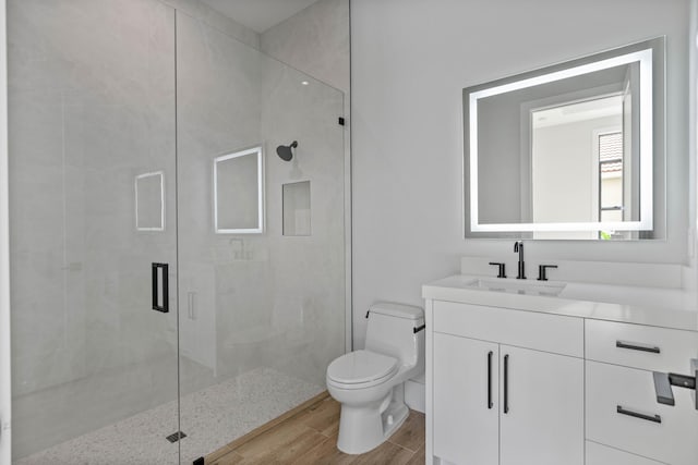 bathroom featuring a shower with shower door, toilet, and vanity