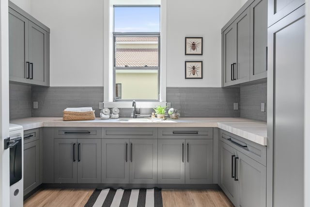 kitchen featuring decorative backsplash, sink, and gray cabinetry