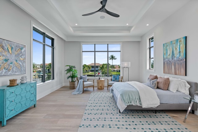 bedroom featuring light wood-type flooring, ceiling fan, and a raised ceiling