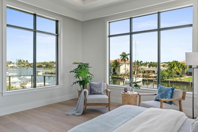 bedroom with light hardwood / wood-style floors and a water view