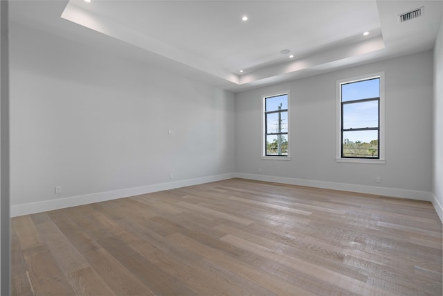 spare room with light hardwood / wood-style floors and a tray ceiling