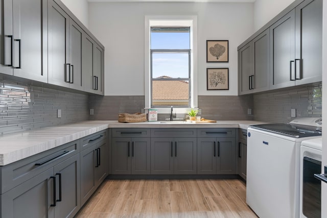 kitchen featuring backsplash, sink, gray cabinetry, and washing machine and clothes dryer