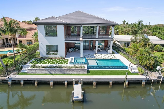 back of property with a swimming pool with hot tub, a water view, a balcony, and a patio