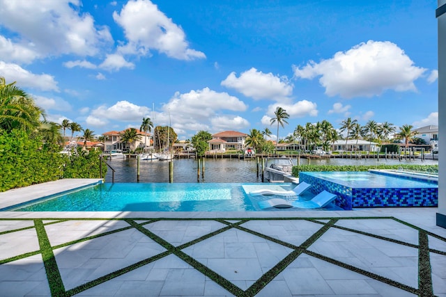 view of pool with a water view, a patio area, and an in ground hot tub