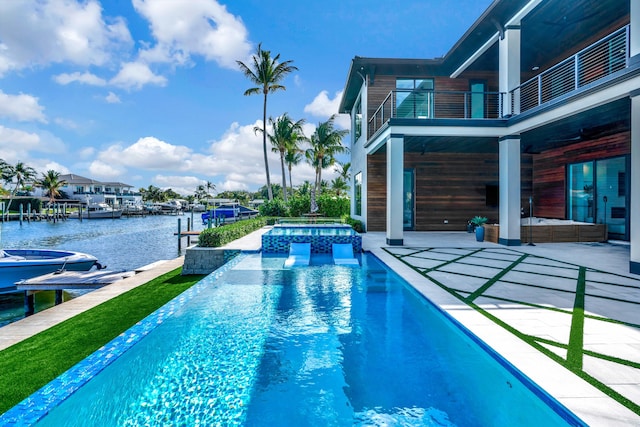 view of swimming pool with an in ground hot tub, a patio area, a boat dock, and a water view