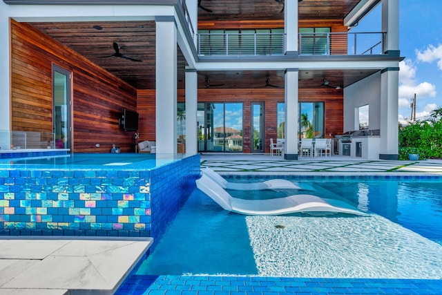 view of pool with ceiling fan, a patio area, and an outdoor kitchen