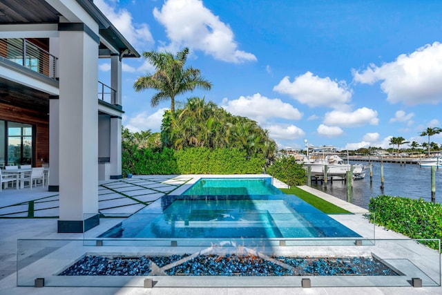 view of swimming pool with a water view, a dock, a fire pit, and a patio