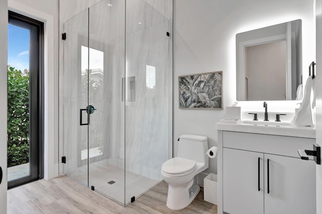 bathroom with vanity, toilet, hardwood / wood-style floors, and an enclosed shower