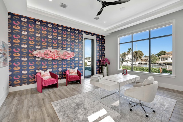 office area featuring a water view, ceiling fan, light hardwood / wood-style floors, and a raised ceiling