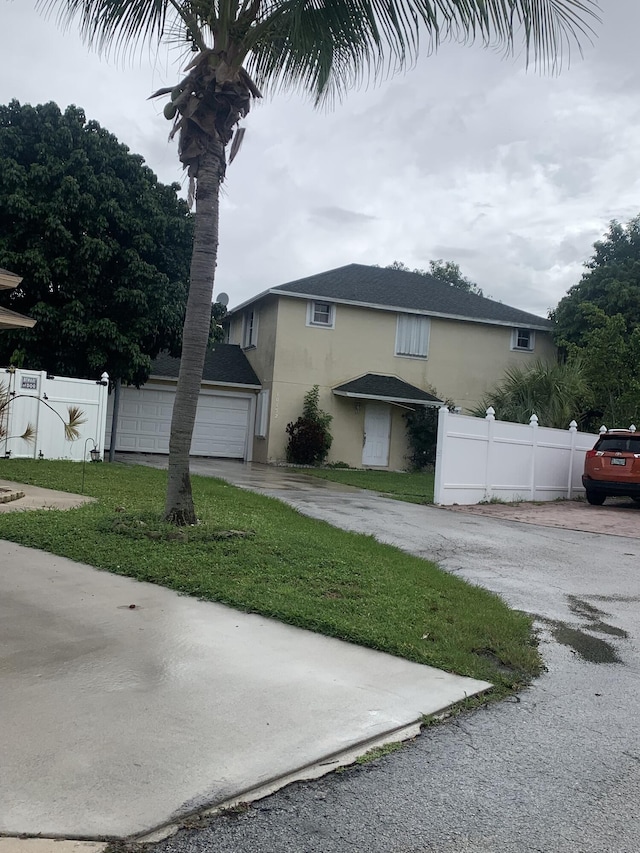 view of side of home featuring a lawn, a detached garage, fence, and stucco siding