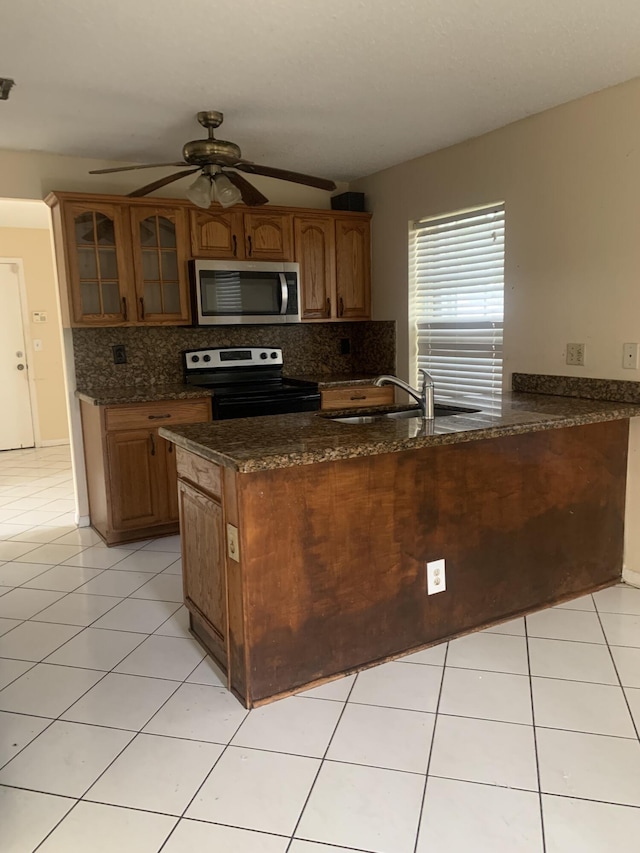 kitchen with dark stone countertops, sink, black electric range, and kitchen peninsula