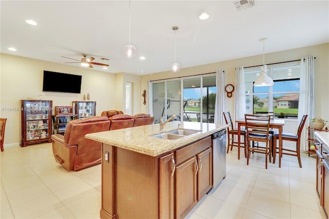 kitchen with pendant lighting, dishwasher, ceiling fan, an island with sink, and light stone counters