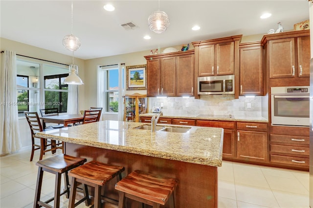 kitchen featuring pendant lighting, a kitchen island with sink, sink, and stainless steel appliances