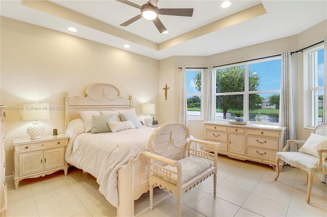 bedroom featuring ceiling fan, a raised ceiling, and light tile patterned floors