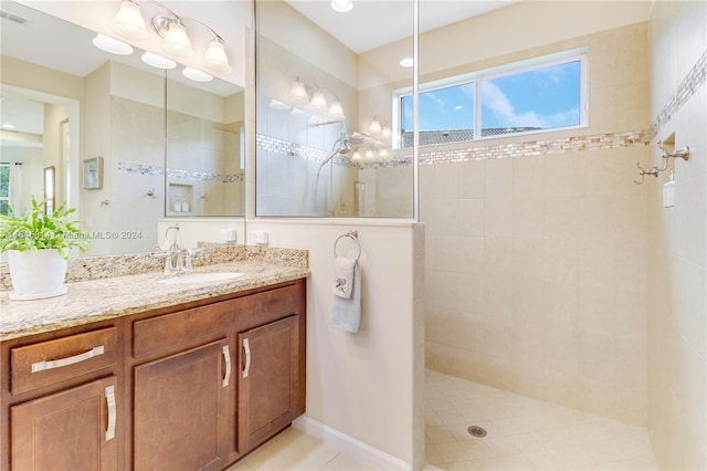 bathroom with a tile shower, tile patterned flooring, and vanity