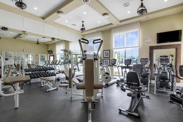 workout area with plenty of natural light, a towering ceiling, and coffered ceiling