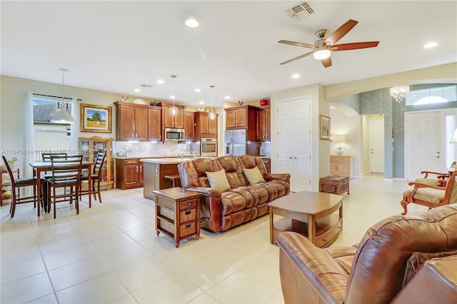 tiled living room featuring ceiling fan with notable chandelier and sink