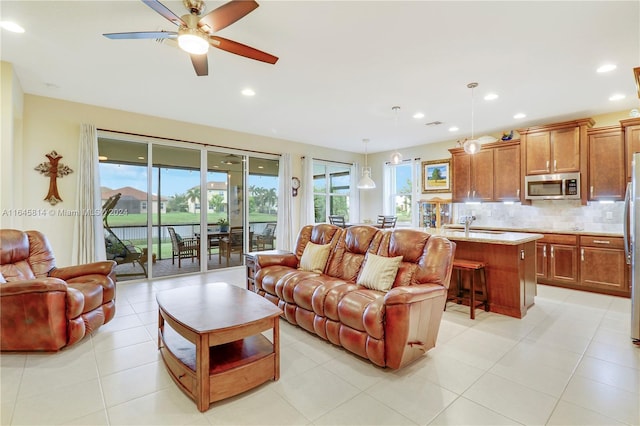 tiled living room featuring a wealth of natural light, ceiling fan, and sink