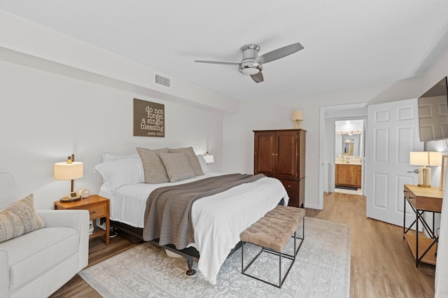 bedroom featuring light hardwood / wood-style flooring, ceiling fan, and ensuite bath