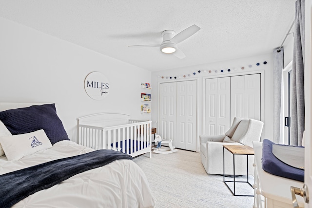 bedroom featuring two closets, a textured ceiling, and ceiling fan