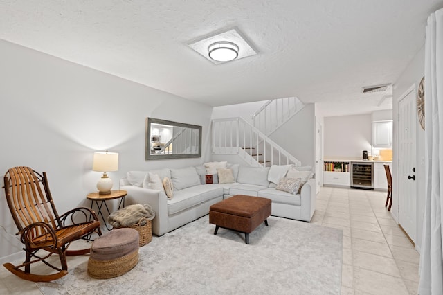 tiled living room featuring beverage cooler and a textured ceiling