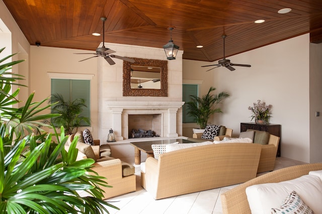 living room featuring vaulted ceiling, ceiling fan, a tile fireplace, light tile patterned floors, and wooden ceiling