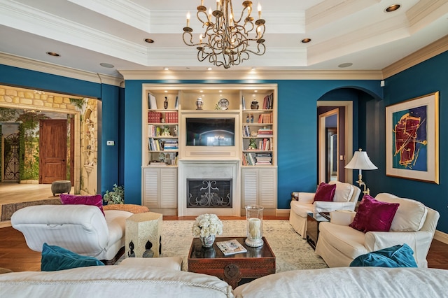 living room featuring hardwood / wood-style floors, a tray ceiling, ornamental molding, and a notable chandelier