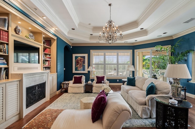 living room with wood-type flooring, a tray ceiling, and ornamental molding