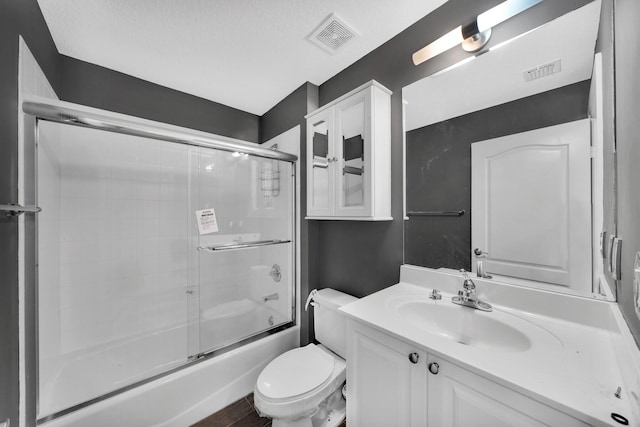 full bathroom featuring a textured ceiling, shower / bath combination with glass door, vanity, and toilet