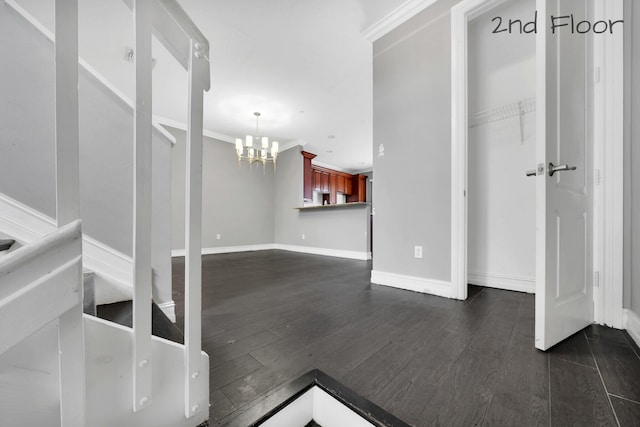 interior space featuring dark wood-type flooring, ornamental molding, and a notable chandelier