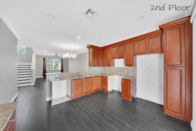 kitchen with decorative light fixtures, kitchen peninsula, sink, and crown molding