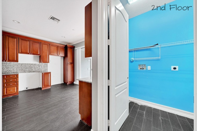 kitchen featuring light stone countertops, backsplash, ornamental molding, and built in desk