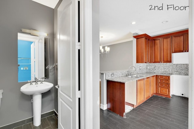 kitchen featuring pendant lighting, tasteful backsplash, sink, ornamental molding, and a chandelier