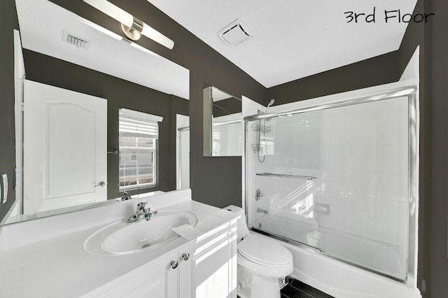 full bathroom with toilet, vanity, and shower / bath combination with glass door