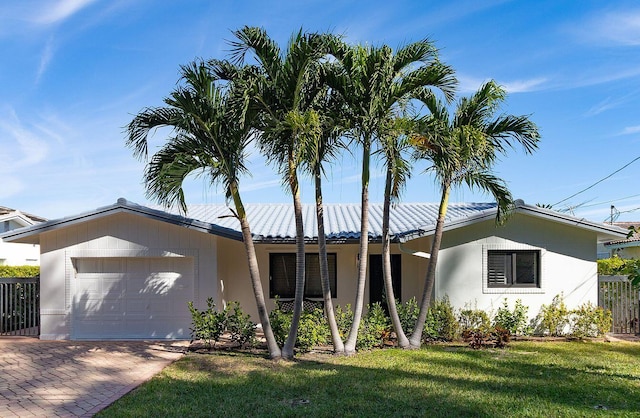 ranch-style house with a garage, fence, decorative driveway, a front lawn, and stucco siding