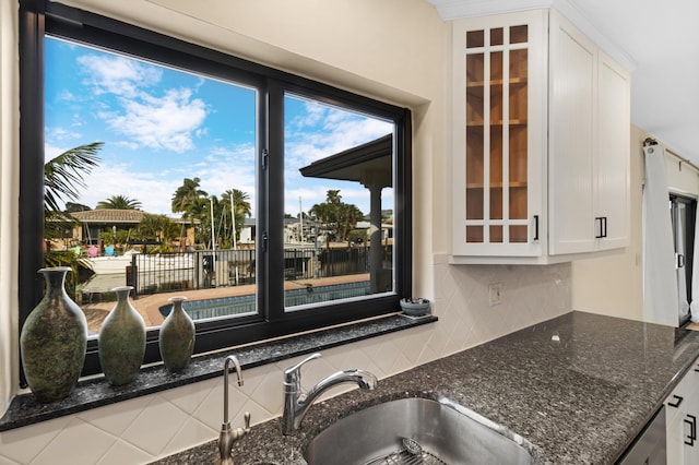 kitchen with white cabinets, dark stone counters, and sink