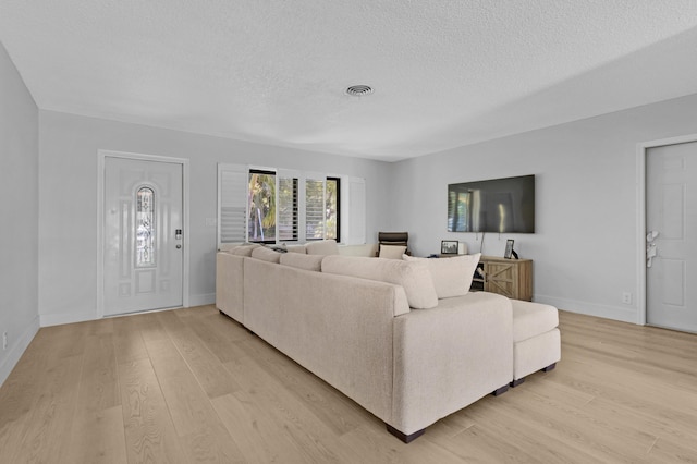 living area with baseboards, visible vents, a textured ceiling, and light wood finished floors