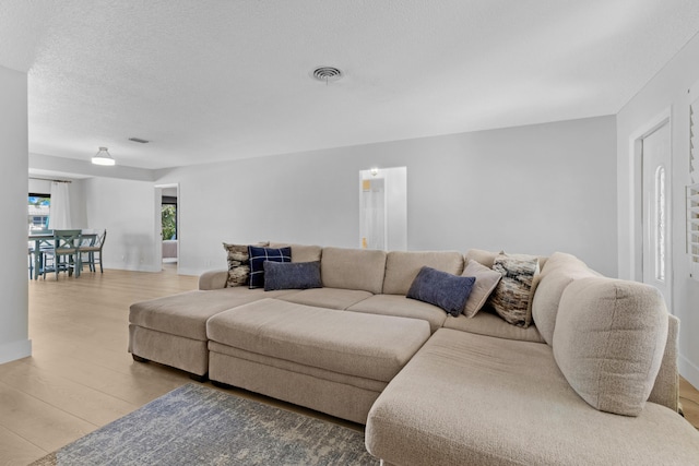 living area with a textured ceiling, visible vents, and wood finished floors