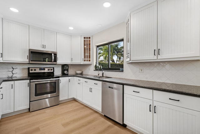 kitchen featuring recessed lighting, a sink, light wood-style floors, appliances with stainless steel finishes, and glass insert cabinets