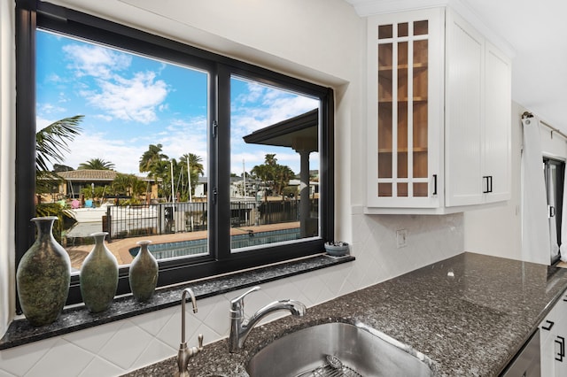 kitchen featuring white cabinetry, a sink, glass insert cabinets, and decorative backsplash