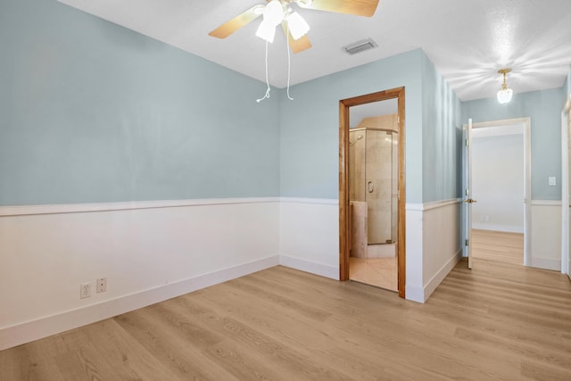 unfurnished bedroom featuring ceiling fan, connected bathroom, and light hardwood / wood-style flooring