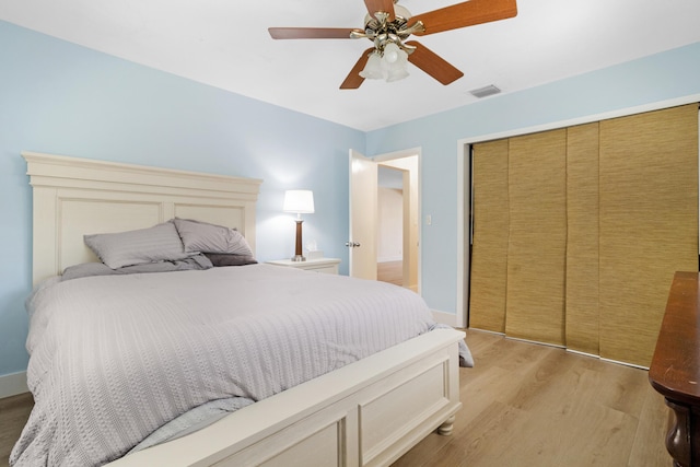 bedroom with visible vents, baseboards, a ceiling fan, light wood-style flooring, and a closet